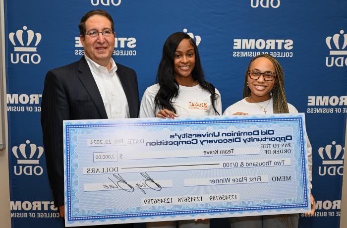 Three individuals pose with a large check